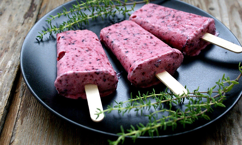 Berry popsicles on plate with herbs
