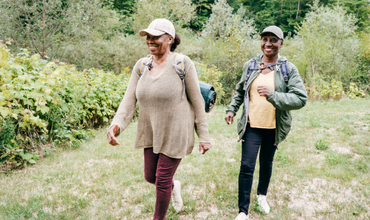 Photo of two African American women hiking outside and smiling, meant to depict the physical and mental benefits of exercise
