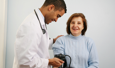Doctor taking an older woman's blood pressure