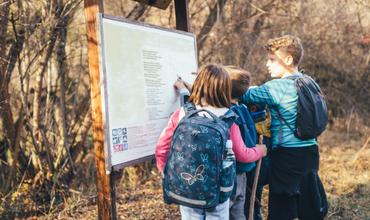 Three children looking at a trail sign on a hike in the fall