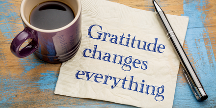 Cup of coffee next to a napkin that reads, Gratitude changes everything."