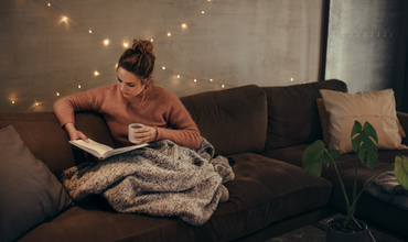 Woman reading book on couch with mug