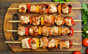 A photo of chicken kebabs layed out on a wooden board.