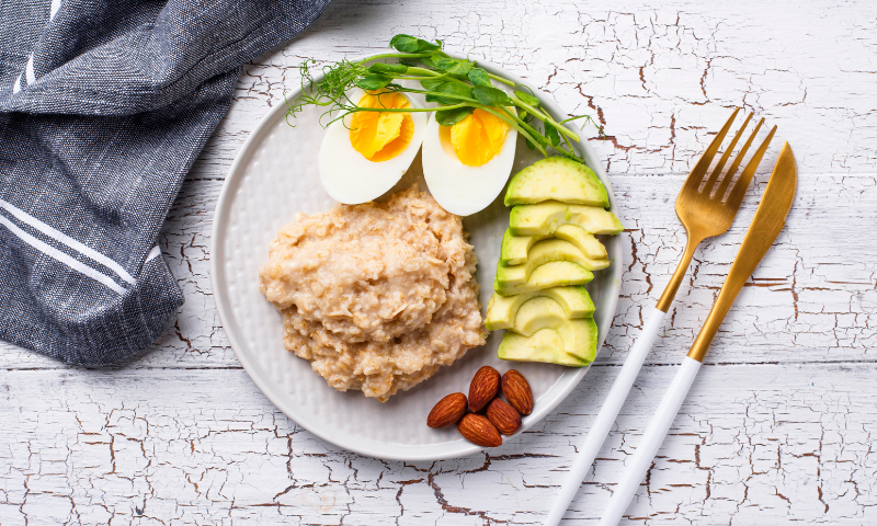 A healthy breakfast featuring eggs and avocadoes along with other foods.