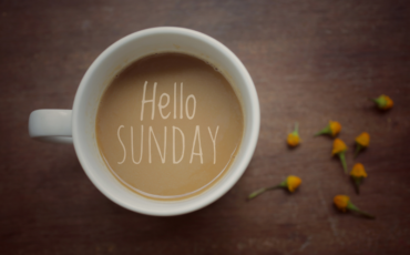 A picture of a coffee with "Hello Sunday" written on the top of the coffee in cream.