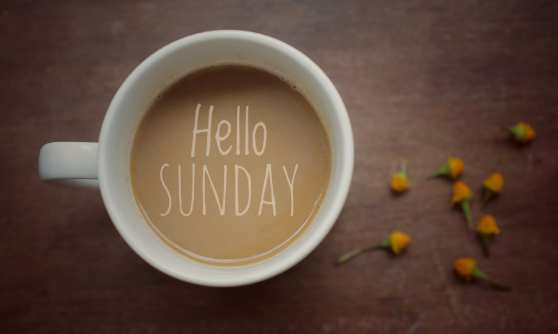 A picture of a coffee with "Hello Sunday" written on the top of the coffee in cream.