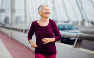 An older woman is shown power walking outside with a smile across her face