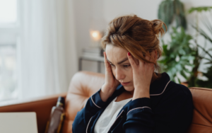Stress woman in bathrobe holds her hands to her temples.
