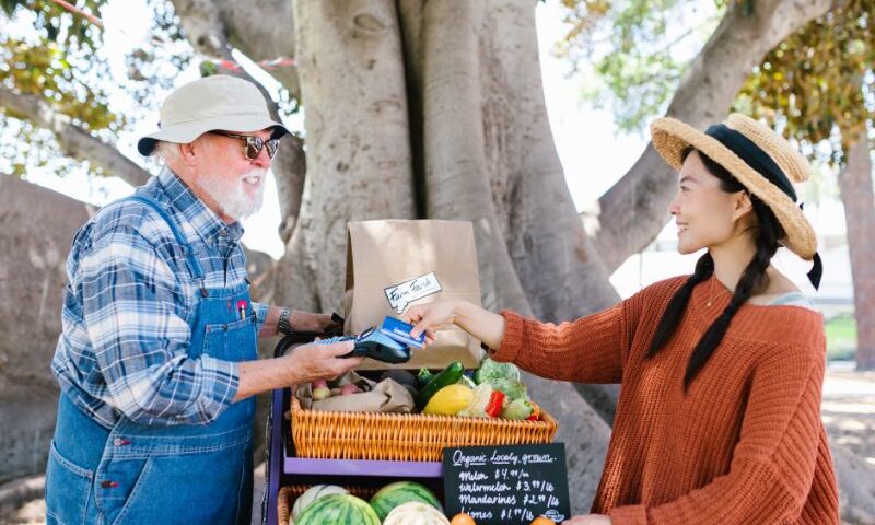 Two people do a transaction at the farmer's market